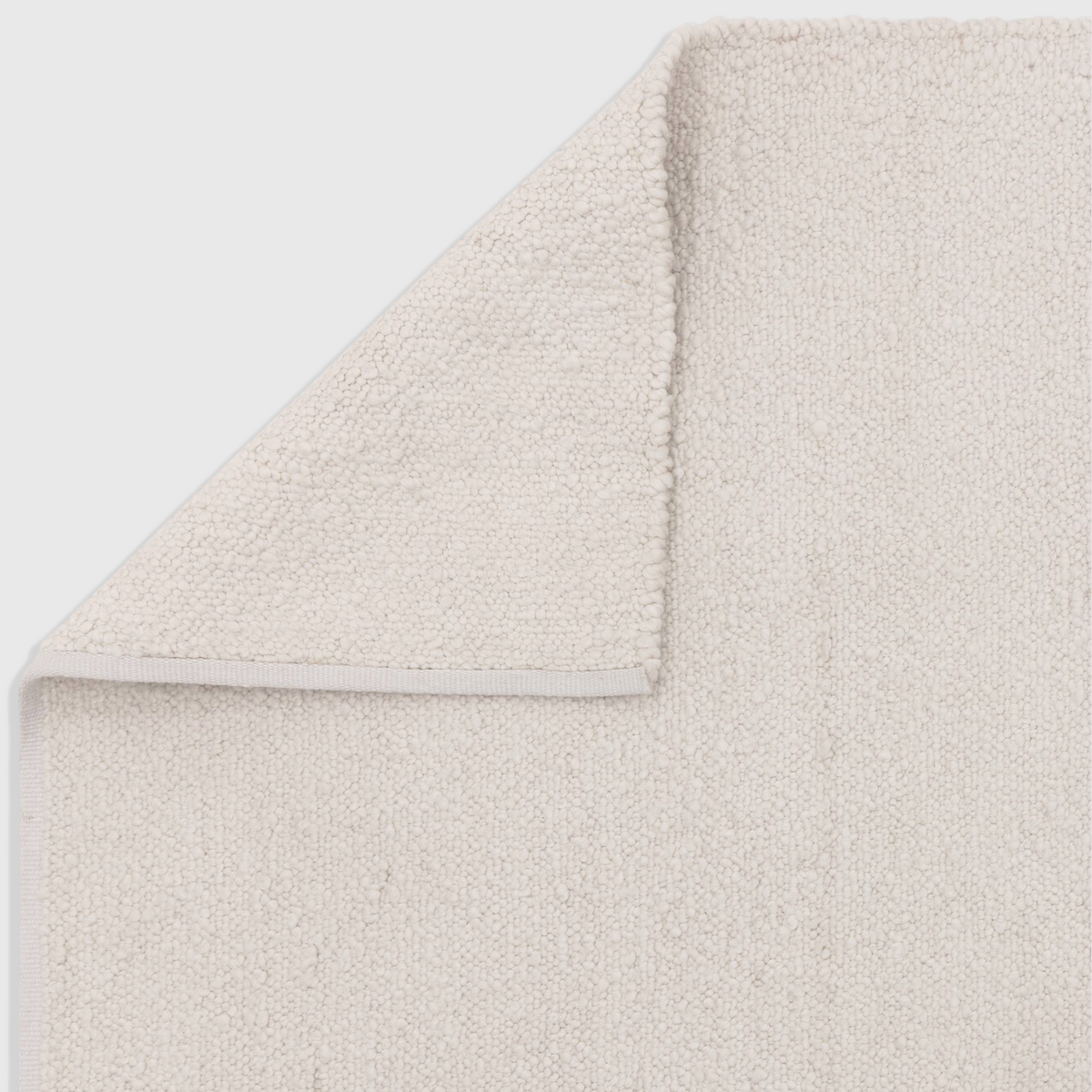 Alvo Rugs Abella ivory boucle rug with a textured hand-woven polyester finish and a folded corner showing the backing.