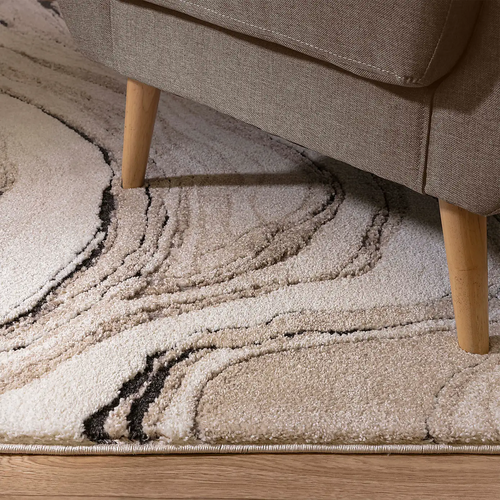 Alvo Rugs Miraga Quartz beige shaggy rug with high-low pile and abstract natural patterns under a modern armchair.