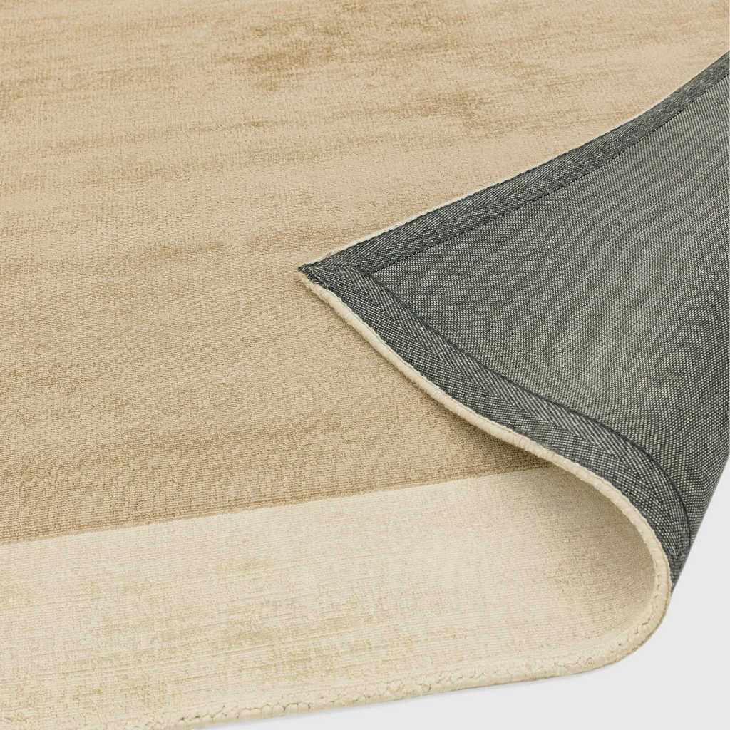 Alvo Rugs Blayde handwoven viscose rug in putty and champagne with a contrasting border and dark grey backing.