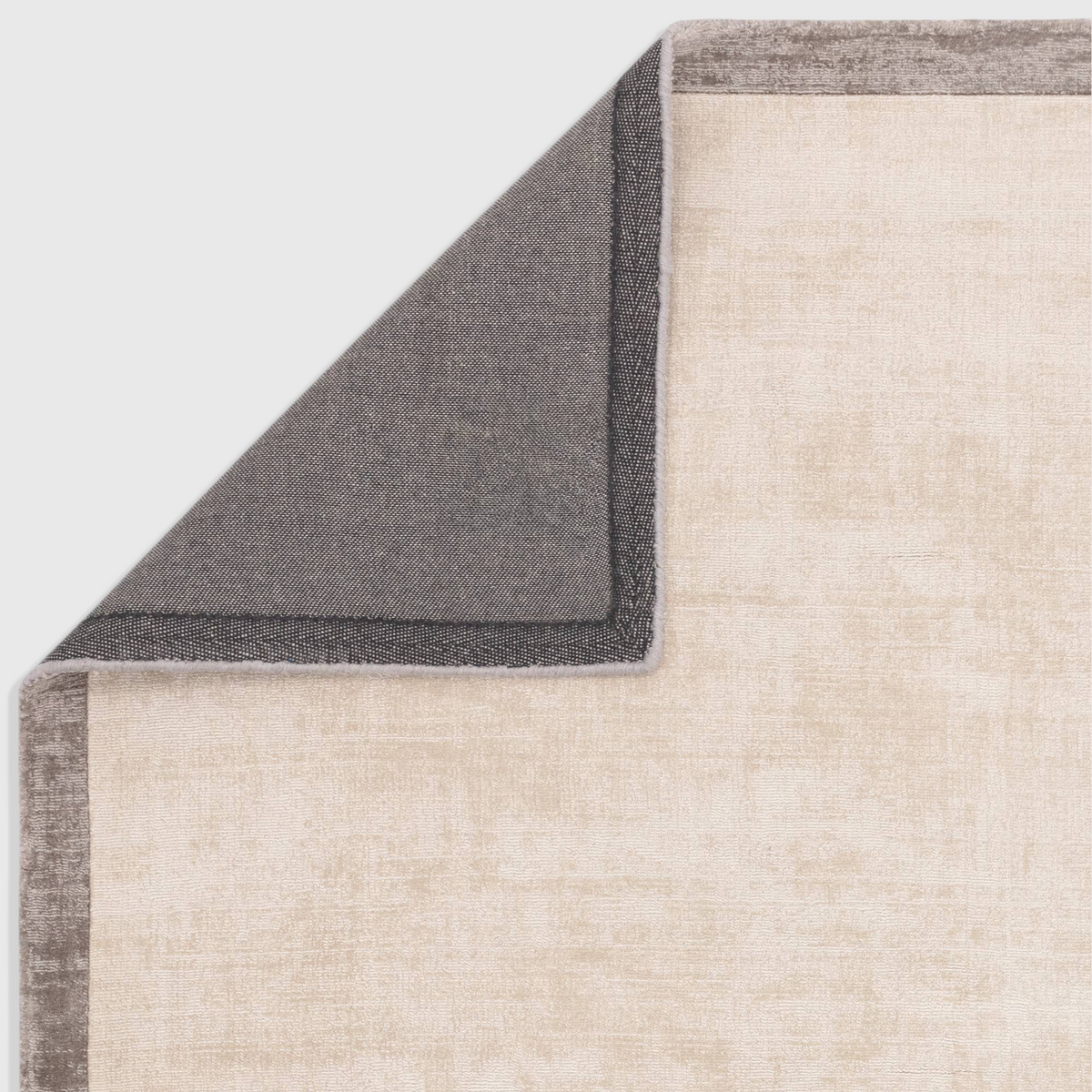 Alvo Rugs Blayde Putty and silver viscose rug showing the dark grey latex backing and corner detail