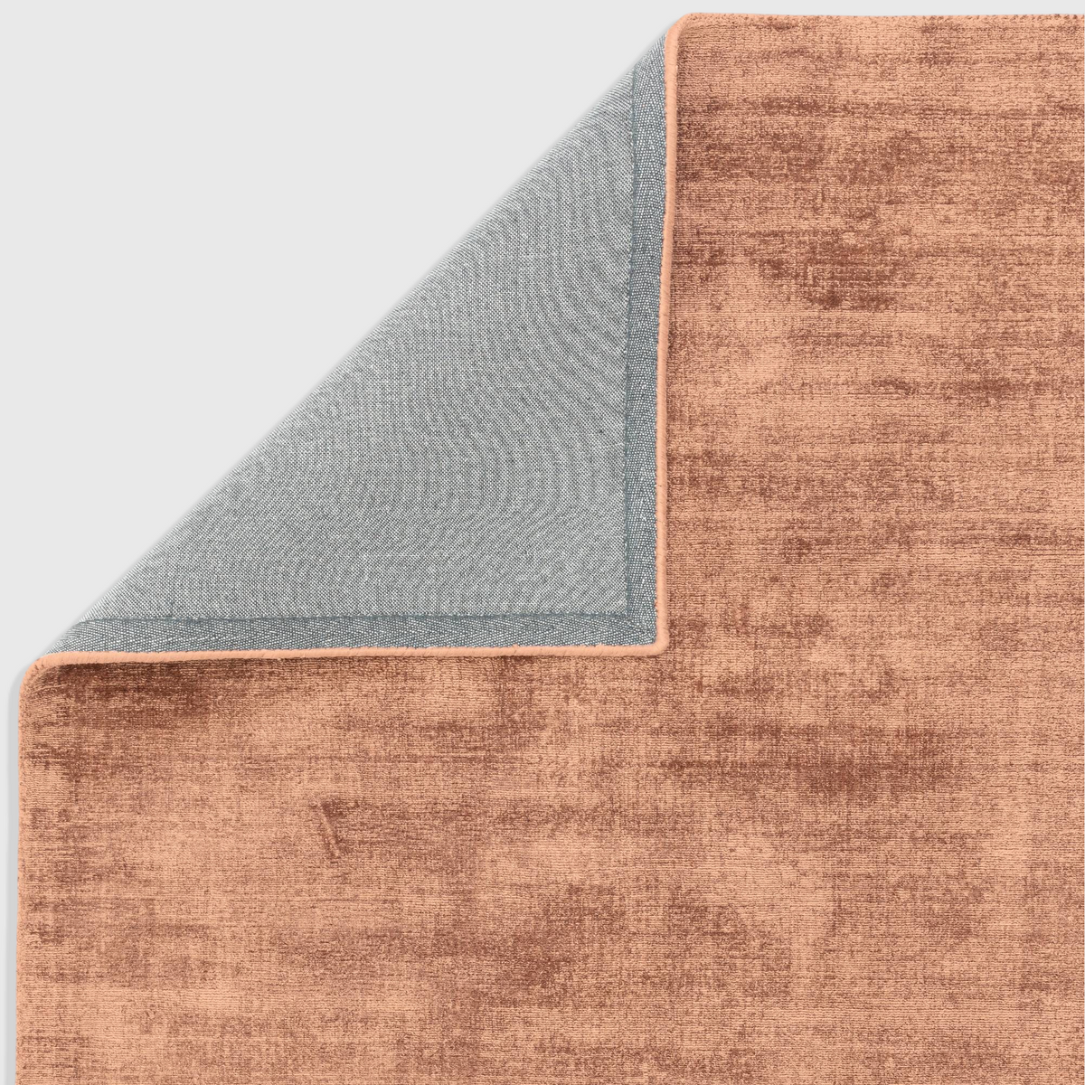 Alvo Rugs Blayde Earth rug in orange viscose with a folded corner showing the grey latex backing and hand-woven pile