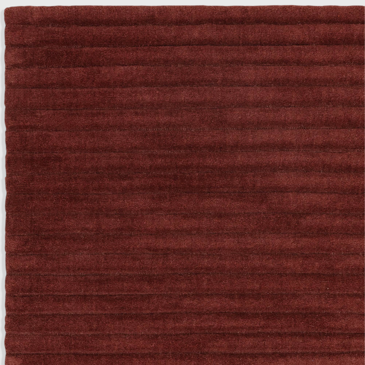 Alvo Rugs Lina burgundy wool rug featuring a textured high-low pile with horizontal ridged stripes.