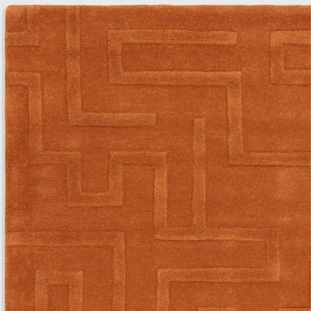 Alvo Rugs Maize Rust wool rug featuring a hand-tufted high-low pile with an ornate geometric maze pattern in orange.