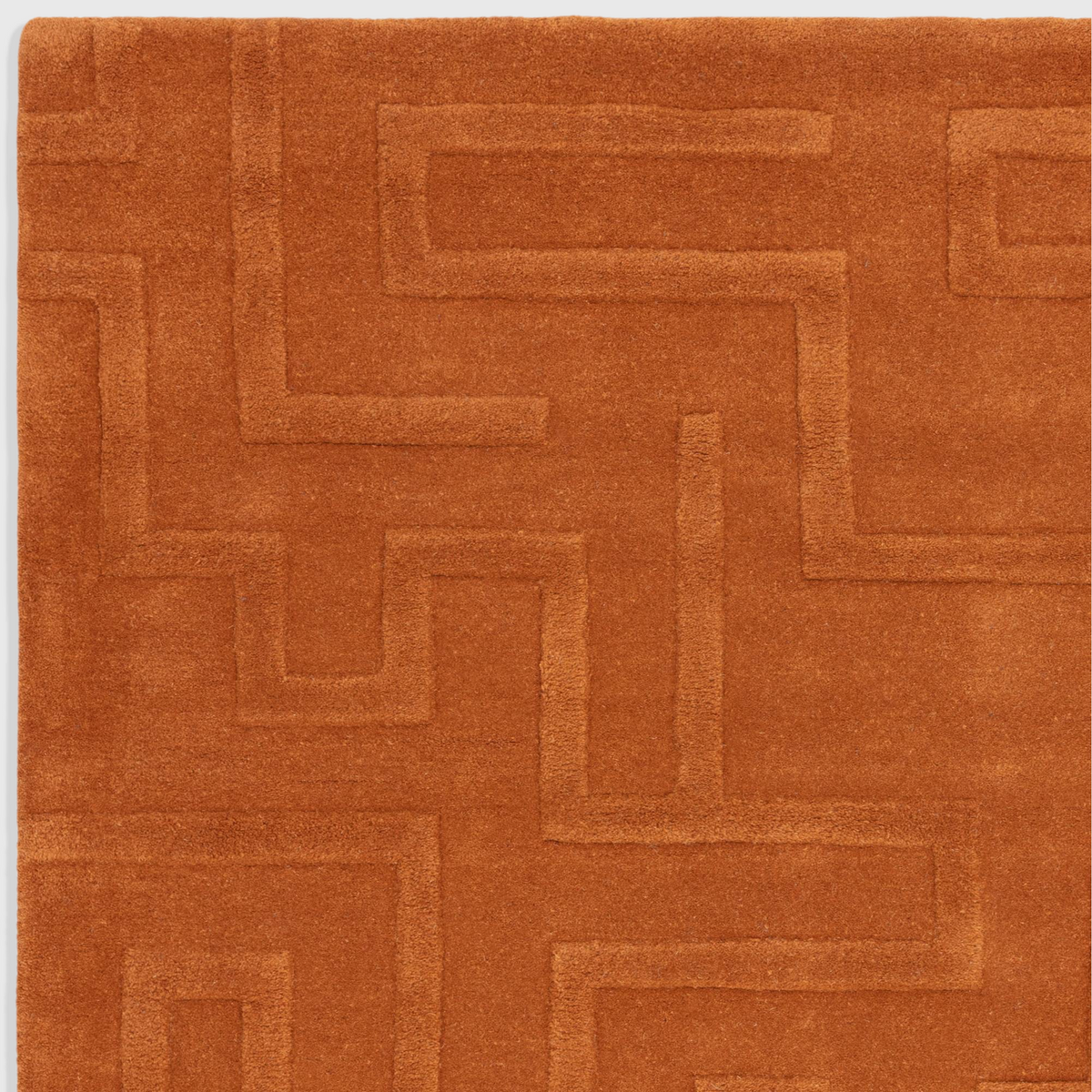 Alvo Rugs Maize Rust wool rug featuring a hand-tufted high-low pile with an ornate geometric maze pattern in orange.
