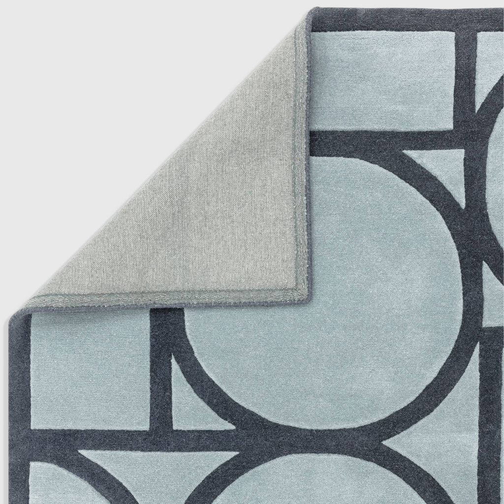 Alvo Rugs Metra blue wool rug with geometric pattern and hand tufted high low pile showing cotton backing corner