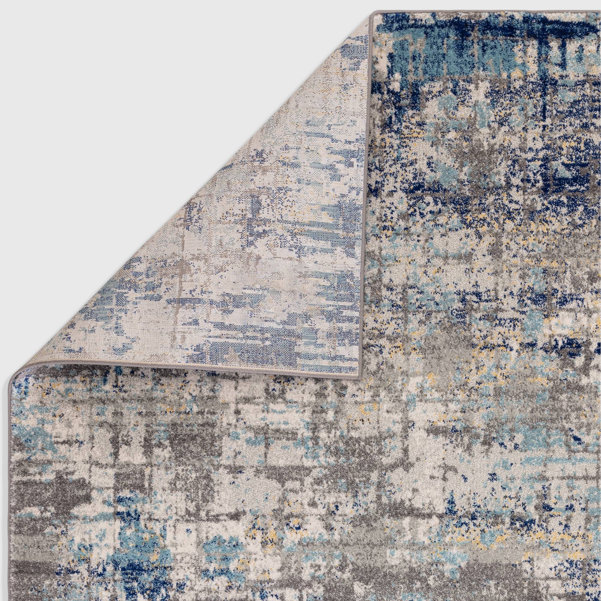 Alvo Rugs Novella Illusion Nv40 abstract rug featuring blue, grey, and yellow tones with a folded corner detail.
