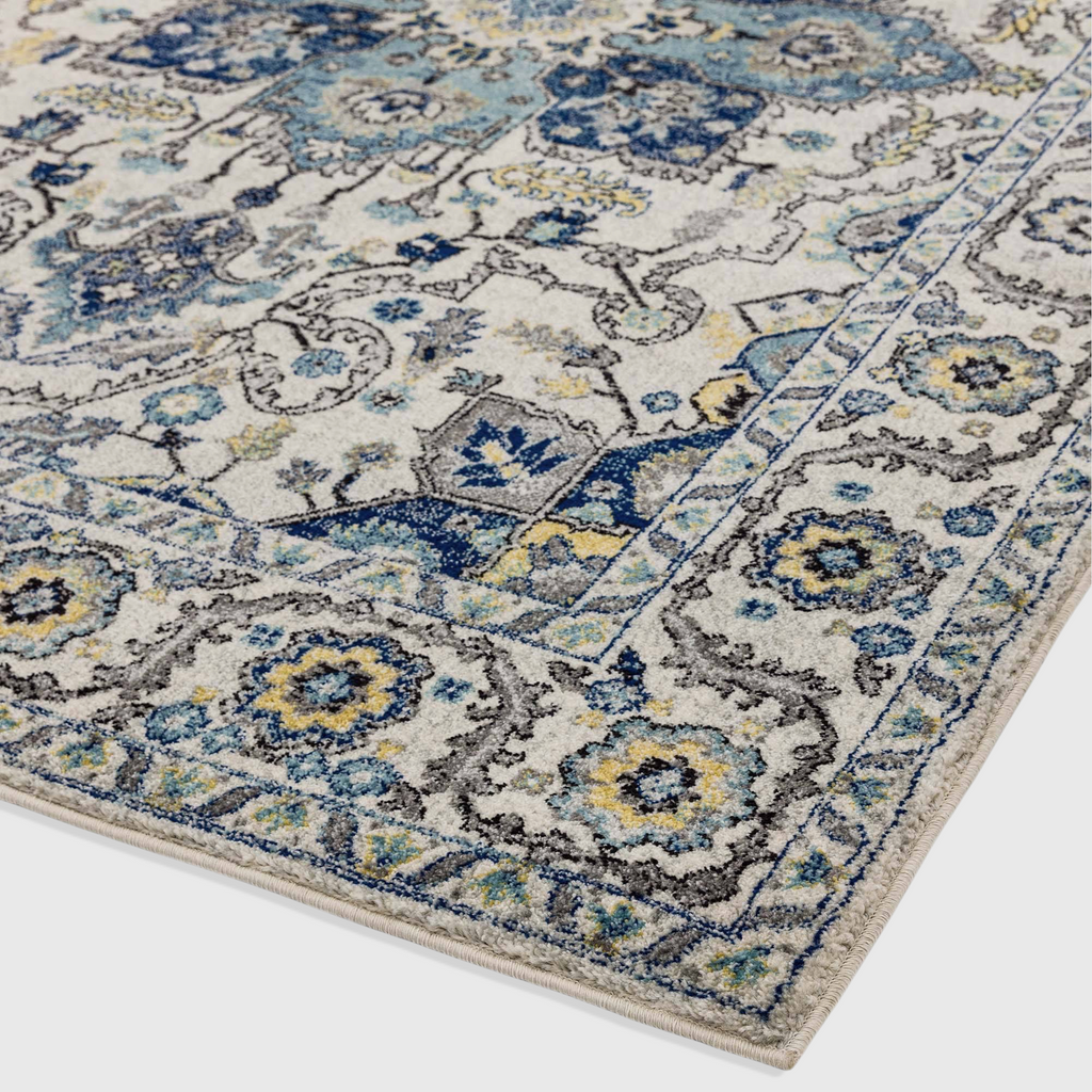 Alvo Rugs Novella Nv25 Persian blue rug with intricate floral patterns in blue, yellow, and grey on a cream background.
