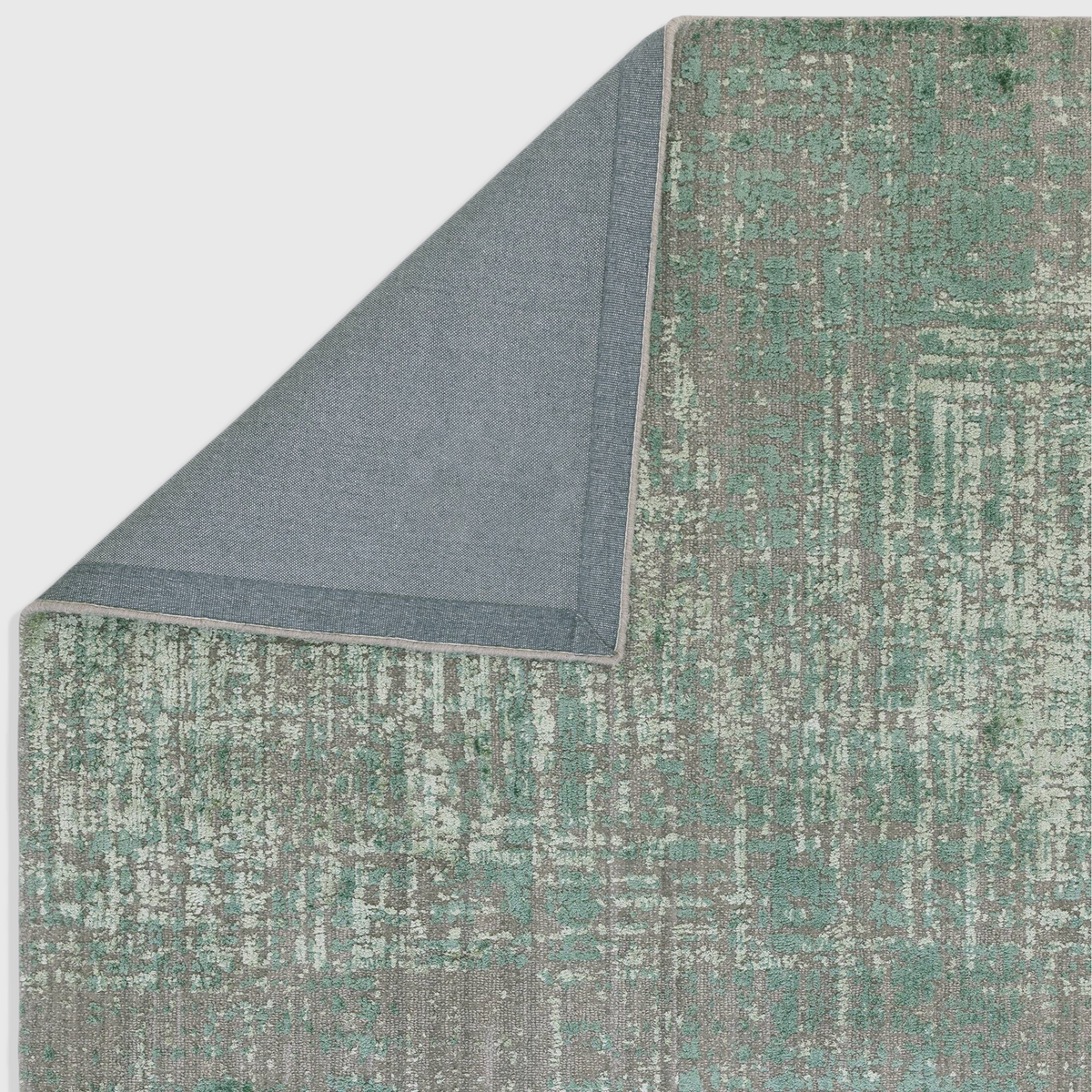 Alvo Rugs Torina forest green abstract rug showing a corner fold to reveal the grey backing and textured pile surface.