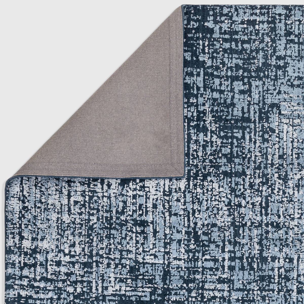 Alvo Rugs Torina petrol blue abstract rug with a folded corner showing the grey backing and textured wool viscose pile