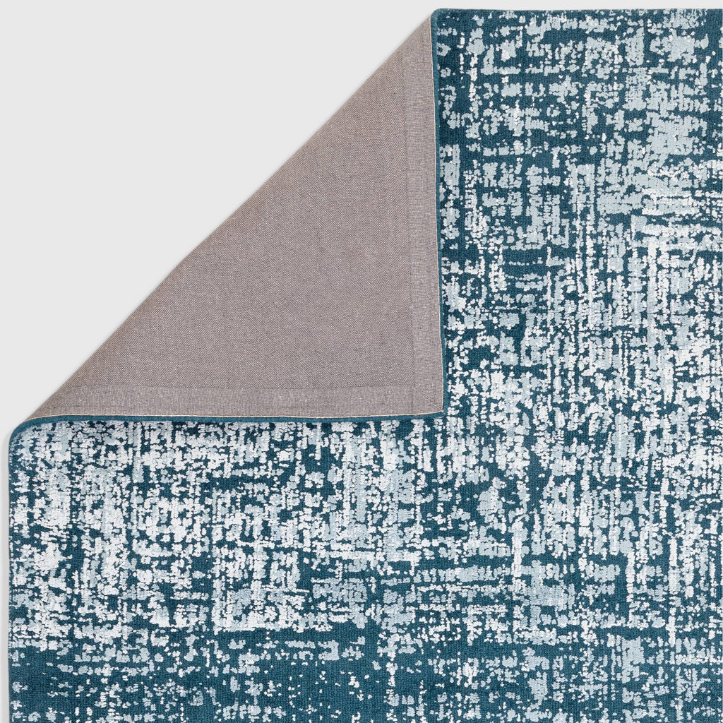 Alvo Rugs Torina teal green abstract rug with a folded corner showing the grey cotton and latex backing